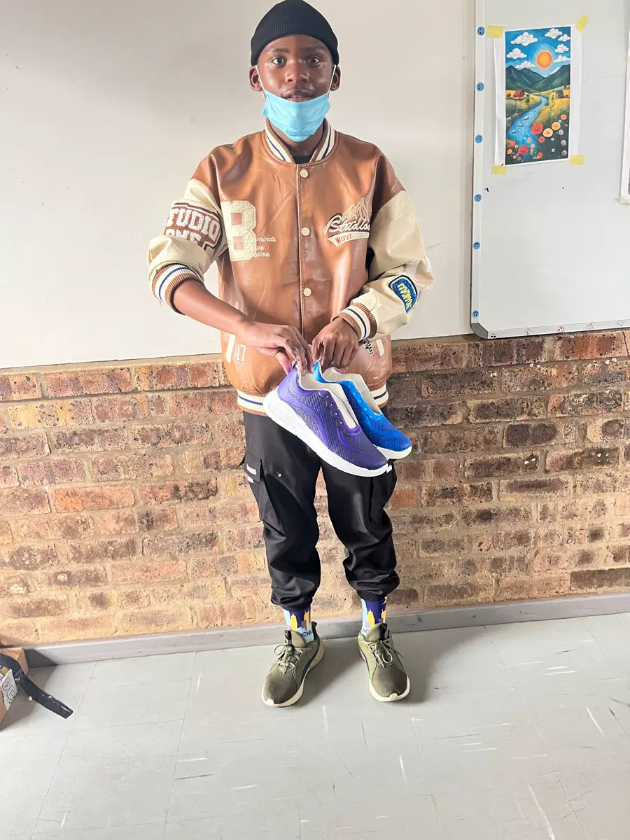 Young man holding up two colourful sneakers