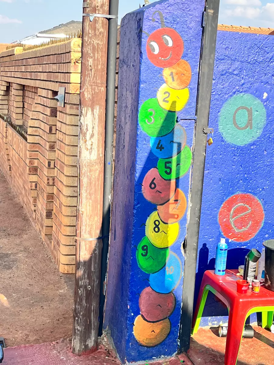 A painted educational mural with a numbered caterpillar on a wall