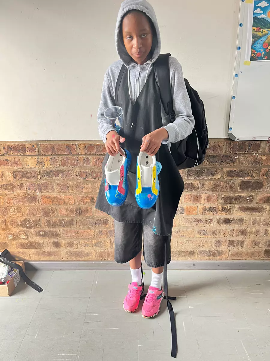 A student holding up a pair of custom-painted sneakers