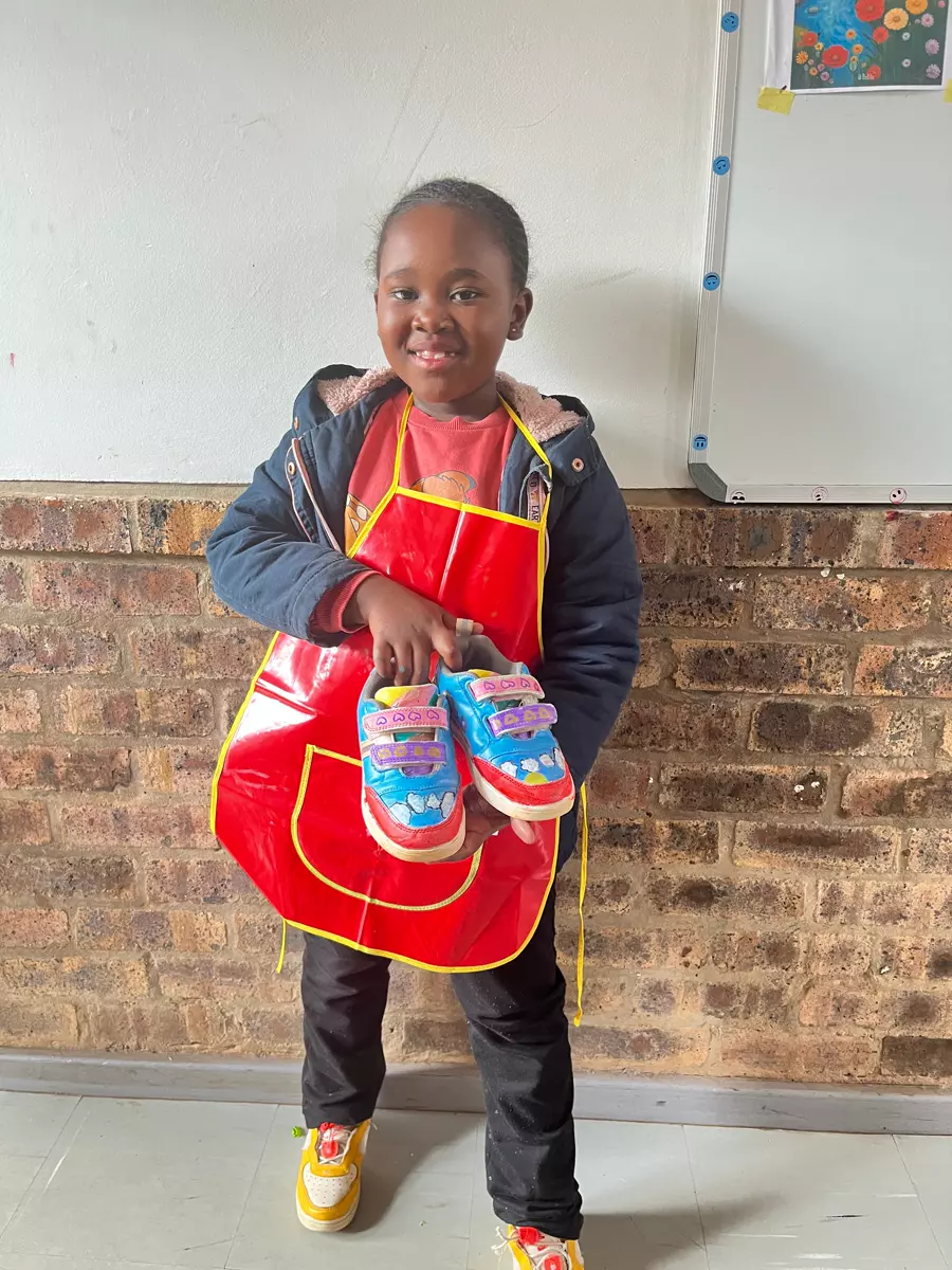 A young girl proudly showing off custom-painted sneakers