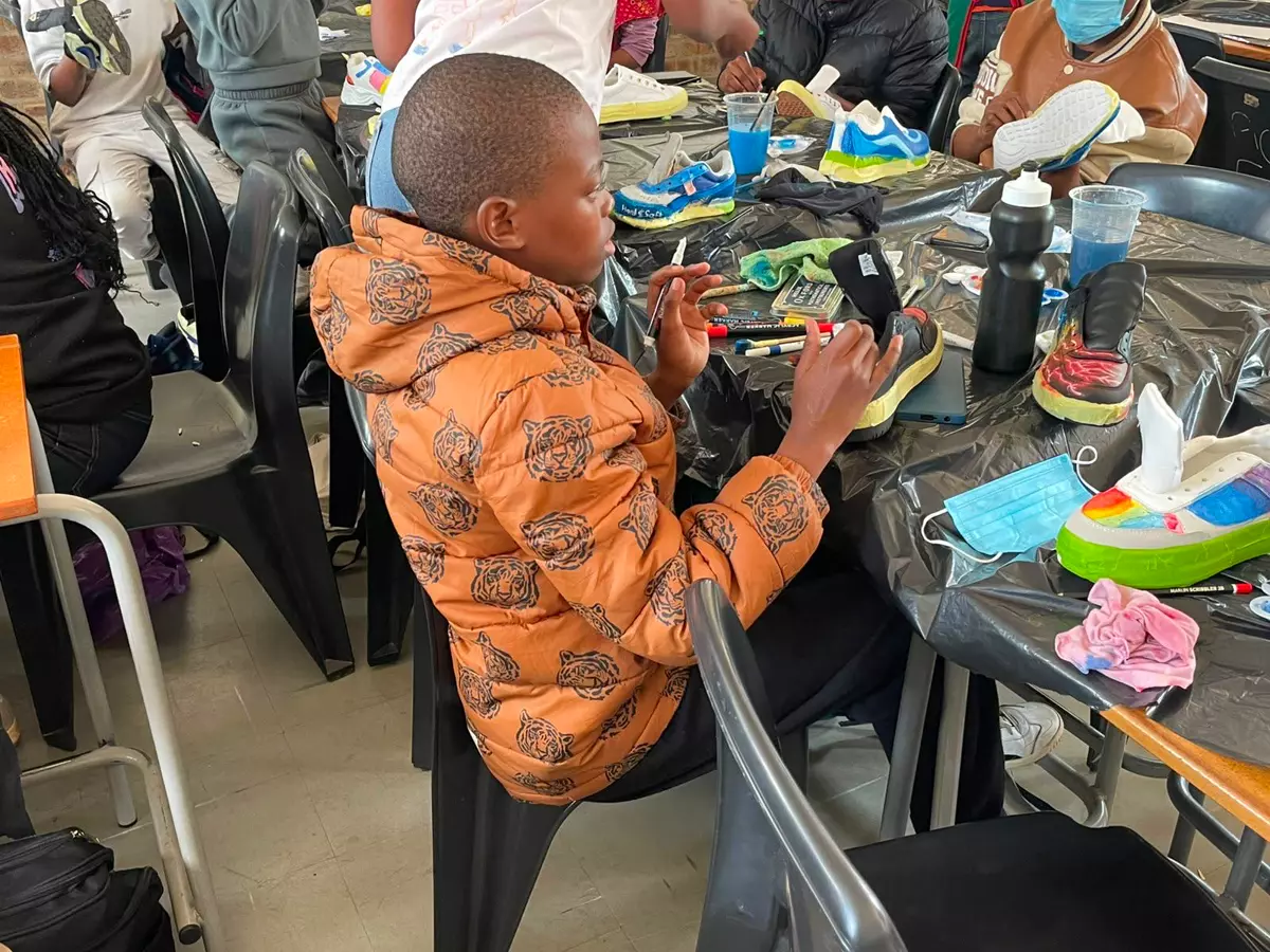 A young boy customizing sneakers at a workshop table