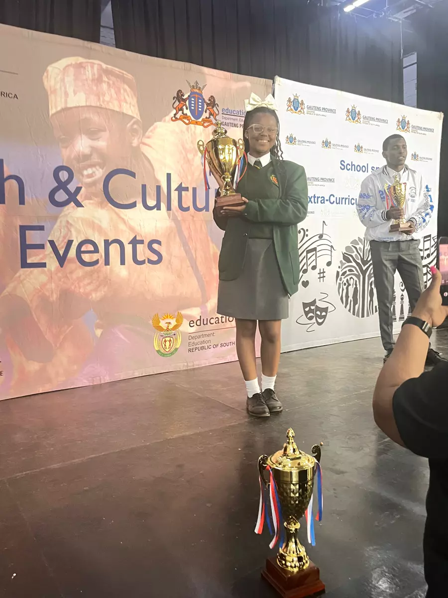 A girl in school uniform holding a trophy on stage