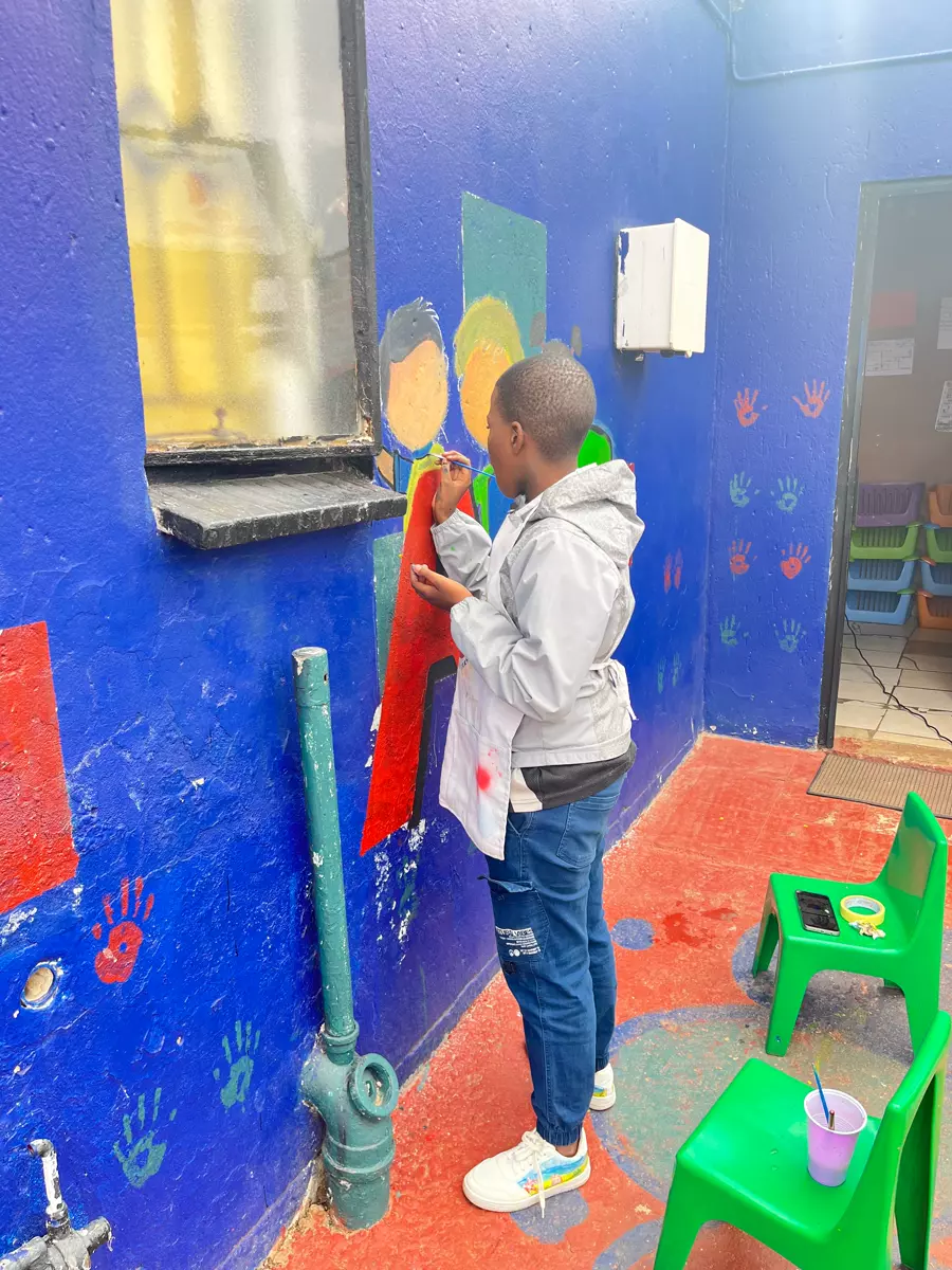 A boy painting a mural on a blue wall